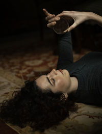 Side view of relaxed female with black hair lying on carpet with transparent crystal ball in room with retro design