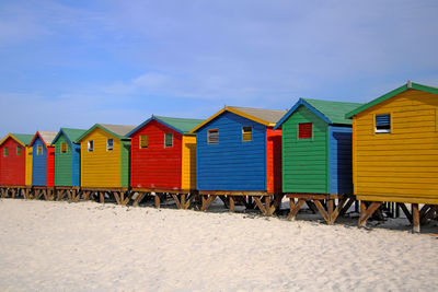 Multi colored huts at beach against sky