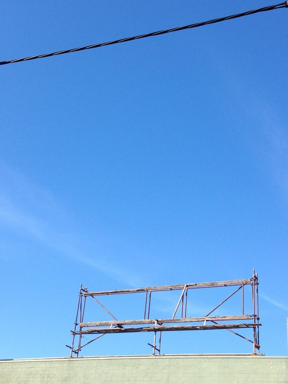 clear sky, low angle view, copy space, blue, built structure, architecture, connection, metal, day, power line, outdoors, sky, fuel and power generation, high section, no people, electricity pylon, sunlight, cable, building exterior, construction