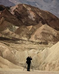Full length rear view of man photographing while standing by mountains