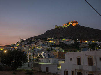 Illuminated buildings in town against sky at night