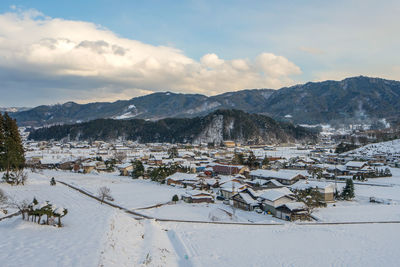 Aerial view of townscape and mountains against sky