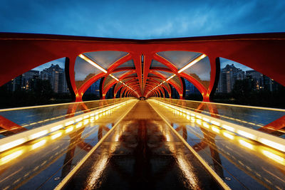 Light trails on bridge in city against sky at night