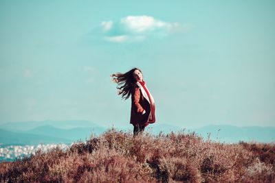 Woman with umbrella standing against sky