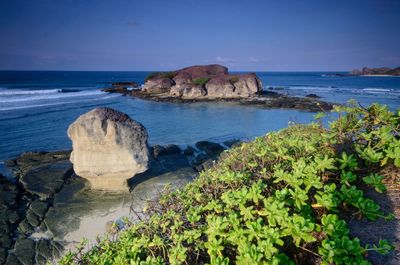 Scenic view of rocks in sea against blue sky