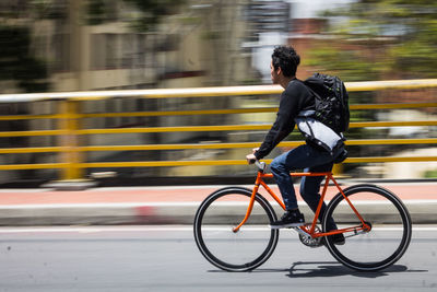 Side view of man riding bicycle on road