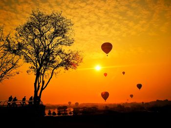 Silhouette hot air balloon against orange sky