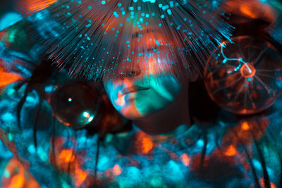 Digital composite image of woman and plasma ball with fiber optics