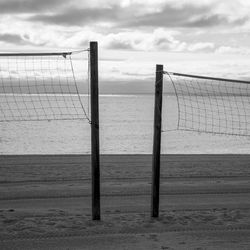 Wooden posts on beach against sky