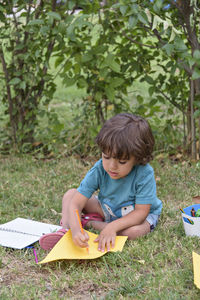 Little boy are using a magic pen to draw pictures in a book on a wooden table in park 