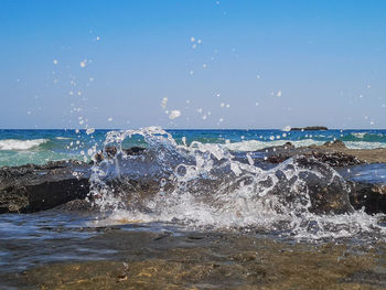 Waves splashing on shore against sky