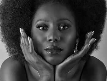 Close-up portrait of young woman against gray background