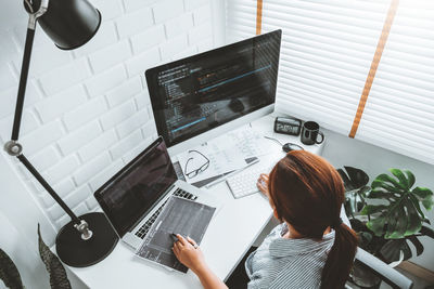 Rear view of woman using laptop on table