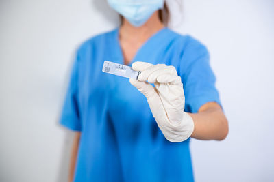 Midsection of doctor holding dentures while standing against white background