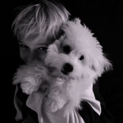 Portrait of young woman with dog against black background