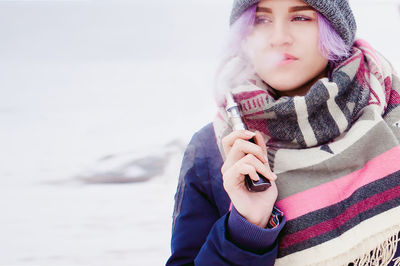 Woman smoking electronic cigarette during winter