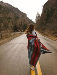 Rear view of woman with umbrella walking on road