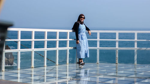 Full length of woman standing against railing