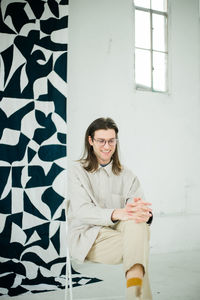 Portrait of young woman standing against wall