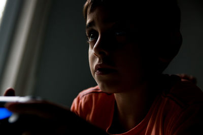 Close-up of thoughtful boy using digital tablet at home