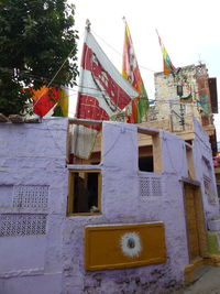Low angle view of flags hanging on building against sky