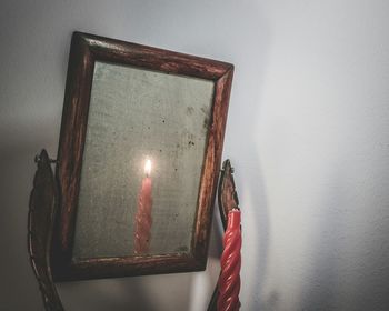 Close-up of lit candle reflecting on mirror