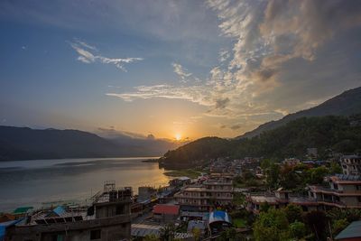 High angle view of buildings by sea against sky during sunset