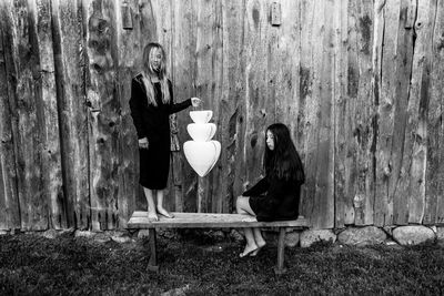 Woman sitting on bench against wall