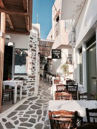 Empty chairs and tables in cafe amidst buildings