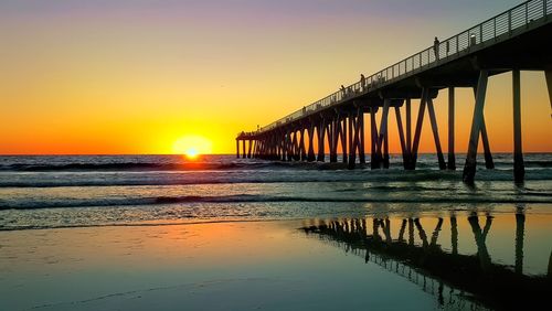 Bridge over sea against sky during sunset