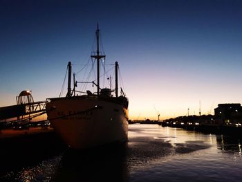 Sailboats moored on sea against sky during sunset