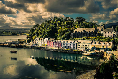 Buildings by river against sky