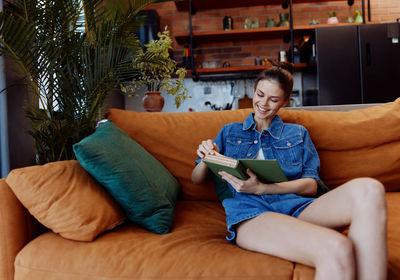 Young woman using laptop while sitting on sofa at home