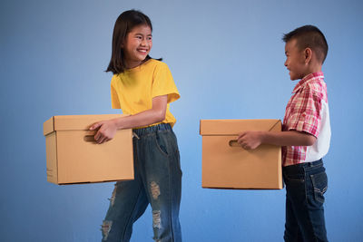 Full length of a boy holding camera in box