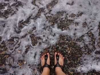 Low section of woman standing on sand at beach