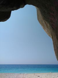 Scenic view of beach against clear sky seen from cave