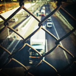 High angle view of truck moving on road seen through chainlink fence