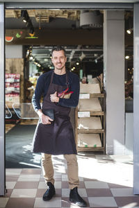 Portrait of smiling mature entrepreneur standing in store