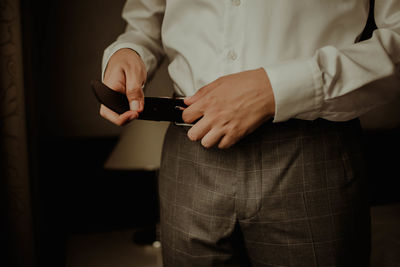 Midsection of man getting dressed while standing at home