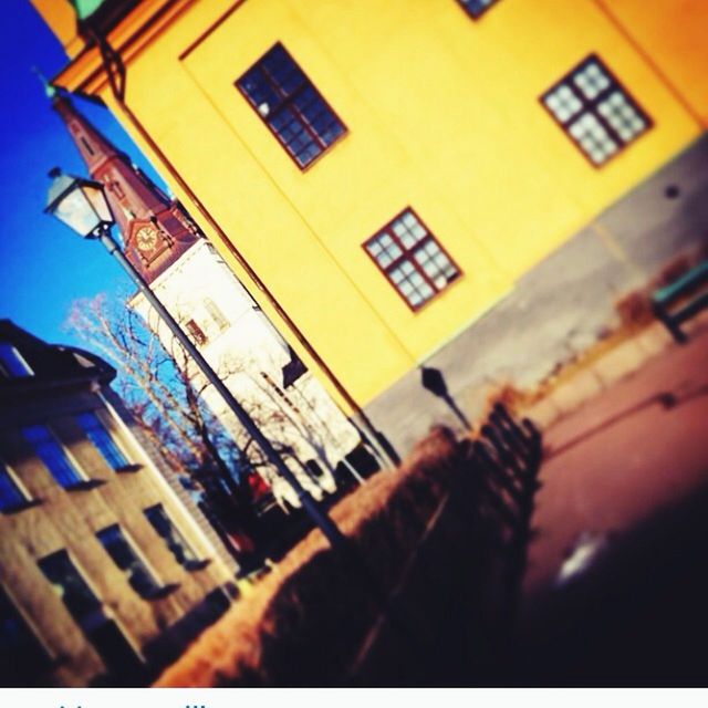 building exterior, architecture, built structure, street, residential building, land vehicle, residential structure, car, transportation, city, building, yellow, mode of transport, low angle view, window, house, outdoors, clear sky, city life, no people