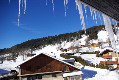 Houses on snow covered landscape against sky