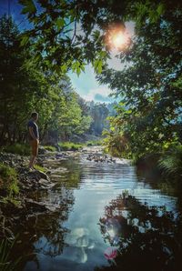 Side view of man standing by lake against sky