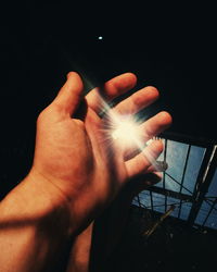 Midsection of man holding illuminated lighting equipment against black background