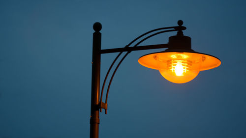 Low angle view of illuminated light bulb against clear sky