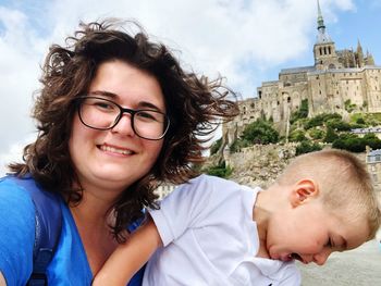 Portrait of smiling woman with son against buildings 