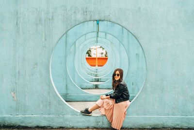 Woman looking down while sitting against wall