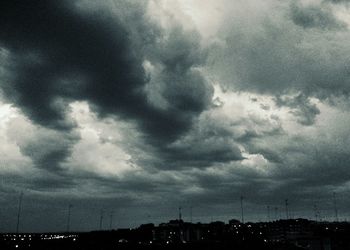 Illuminated cityscape against cloudy sky at dusk