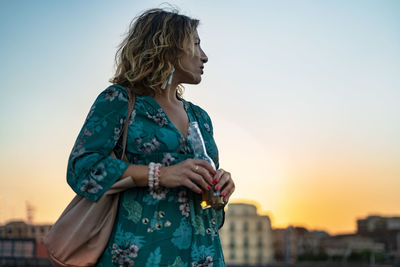 Young woman looking away against sky during sunset