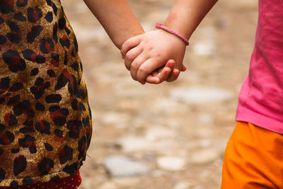 Midsection of friends holding hands outdoors