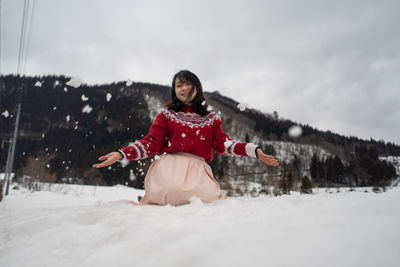 Portrait of smiling woman kneeling on snow